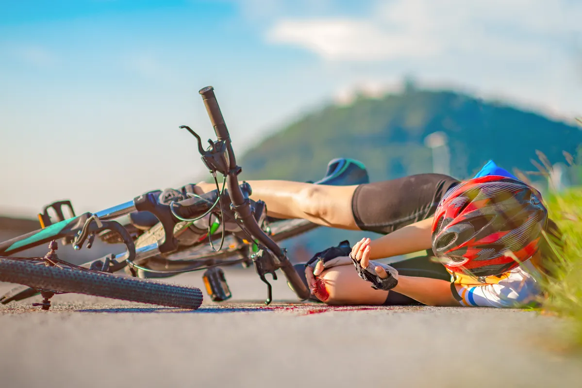 arafed man laying on the ground next to a bike with his foot on the ground