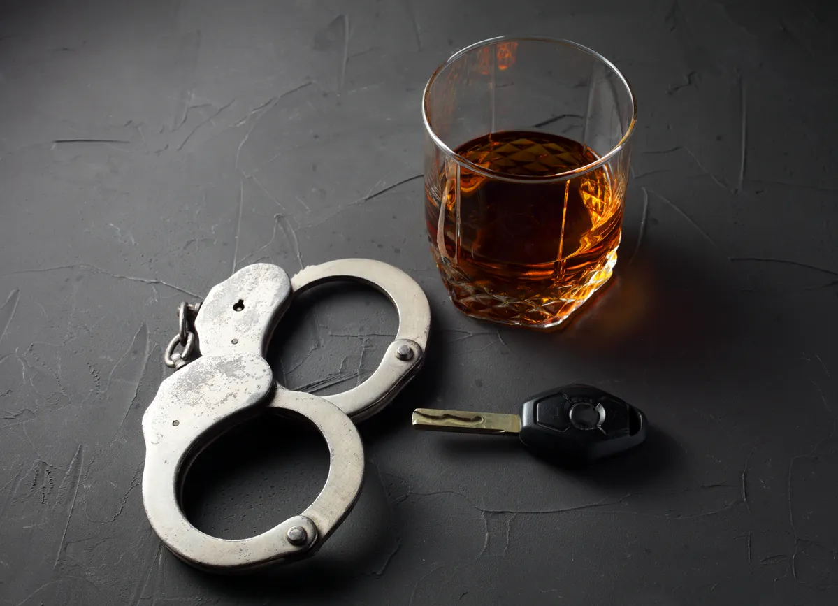 handcuffs near car keys and alcohol