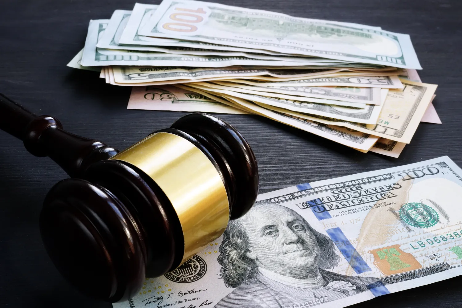 Image of a gavel surrounded by money to represent legal fines