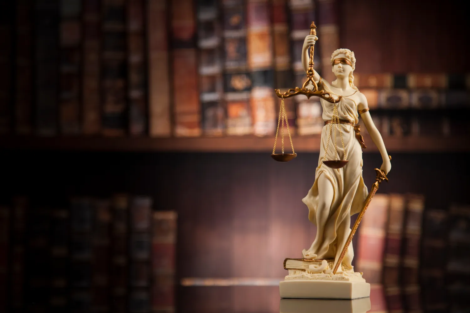 Image of Lady Justice in front of a bookshelf of law books