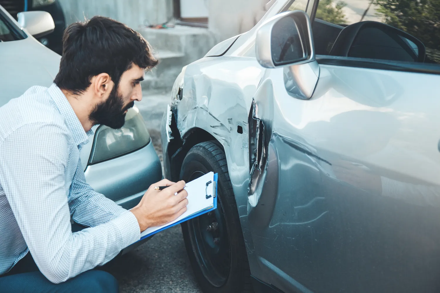 Image of an insurance adjuster analyzing a car