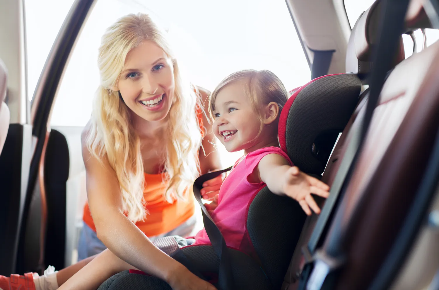 Mother putting her child into a car seat.